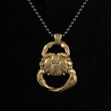 Gold crab pendant necklace on black background, perfect for gift or personal wear.
